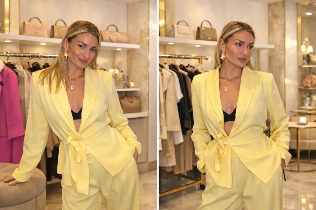 Donna sorridente che indossa un elegante completo giallo chiaro in un negozio di moda, con borse appese sullo sfondo.